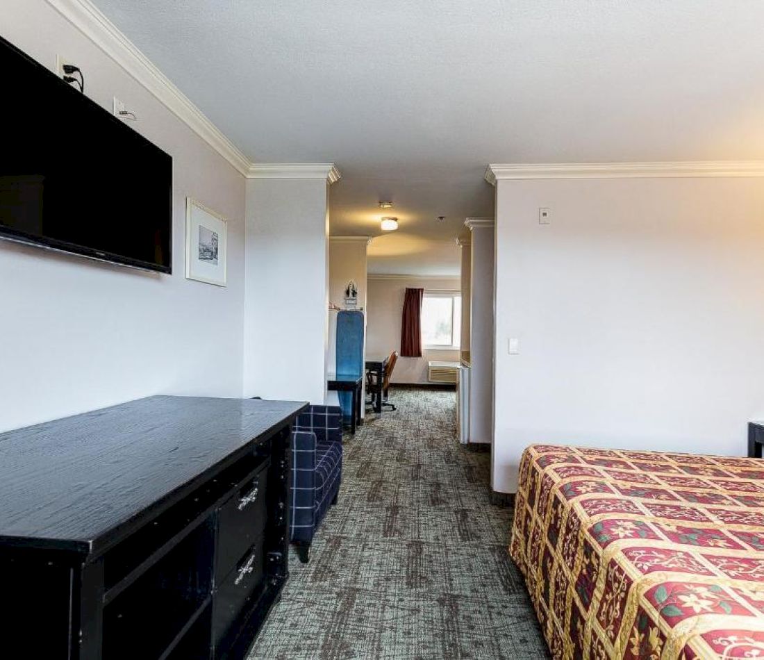 A wide view of a hotel room with a bed, TV, and desk.