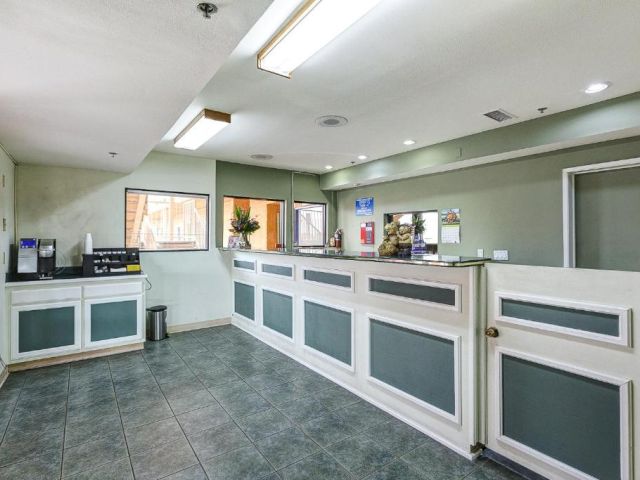 A hotel lobby with a reception desk, coffee machine, and tiled floor.