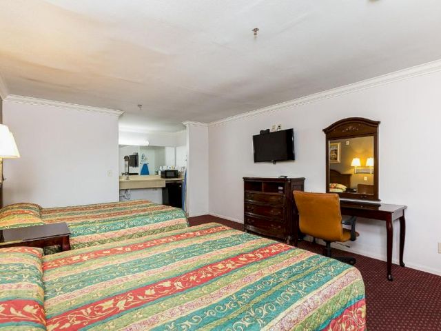 A hotel room with two beds, a desk, and a TV on the wall.